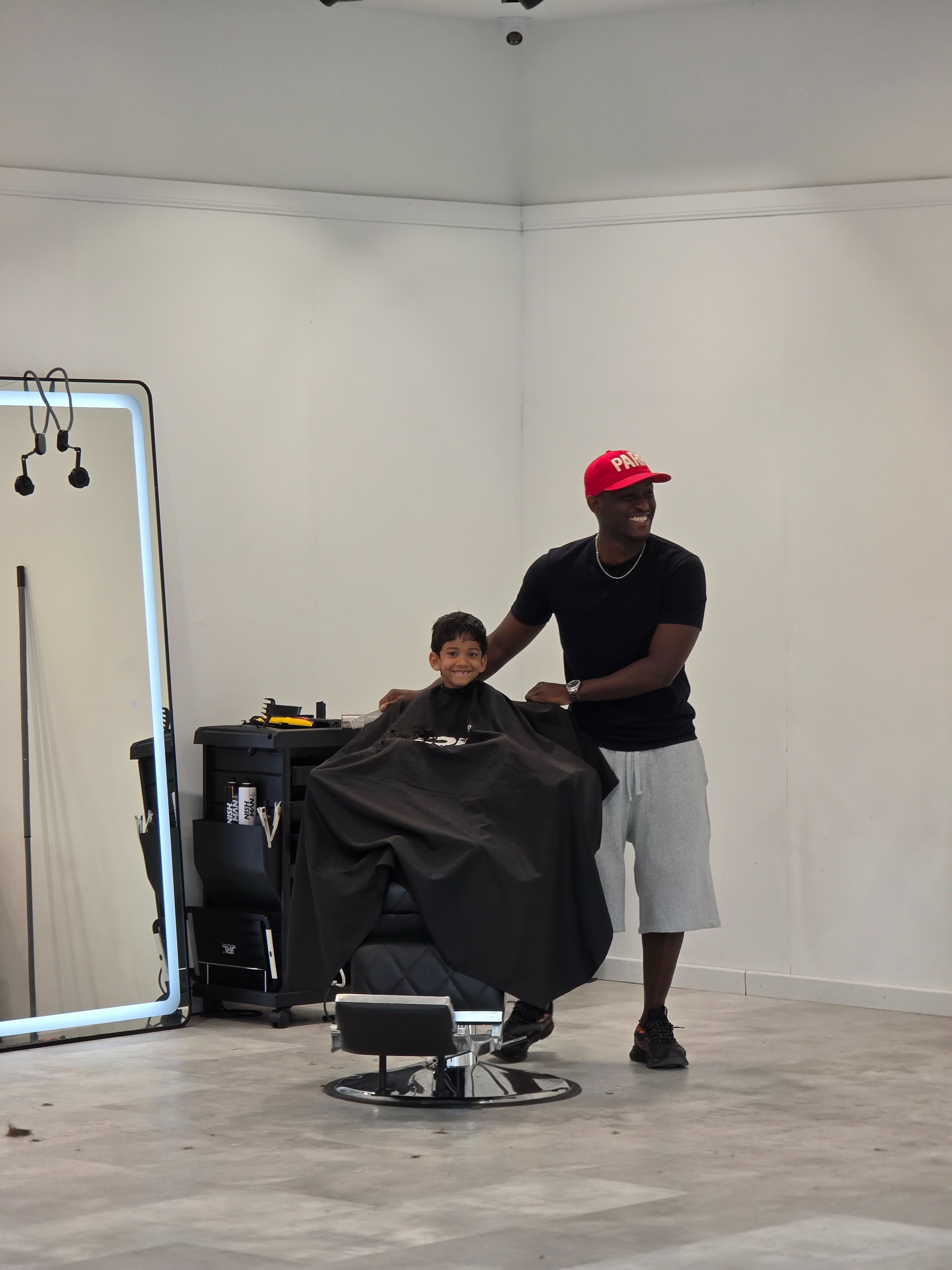 Een barber knipt een jongen in de witte studio
