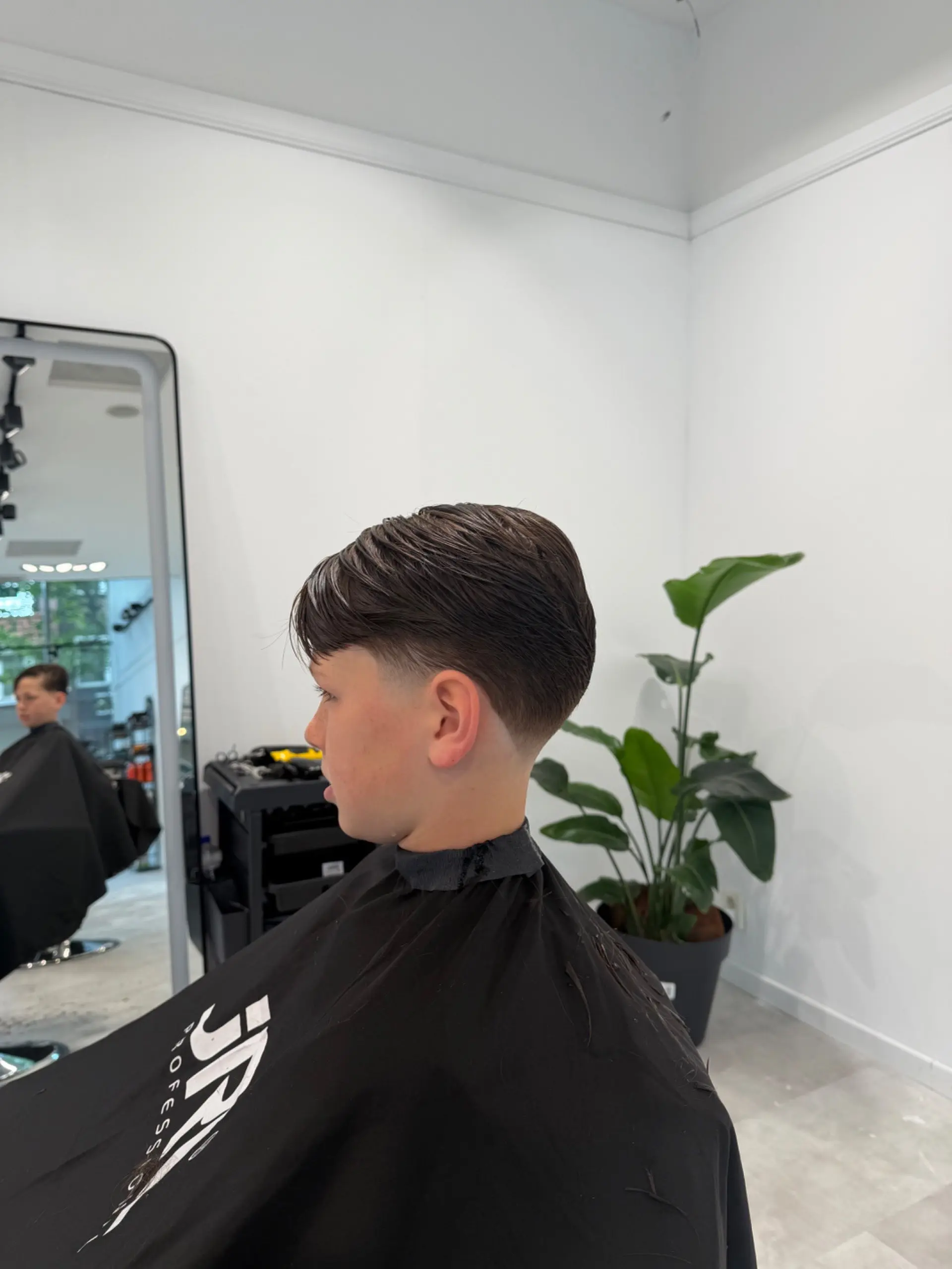 Jongen met een verse cut in profiel voor de spiegel